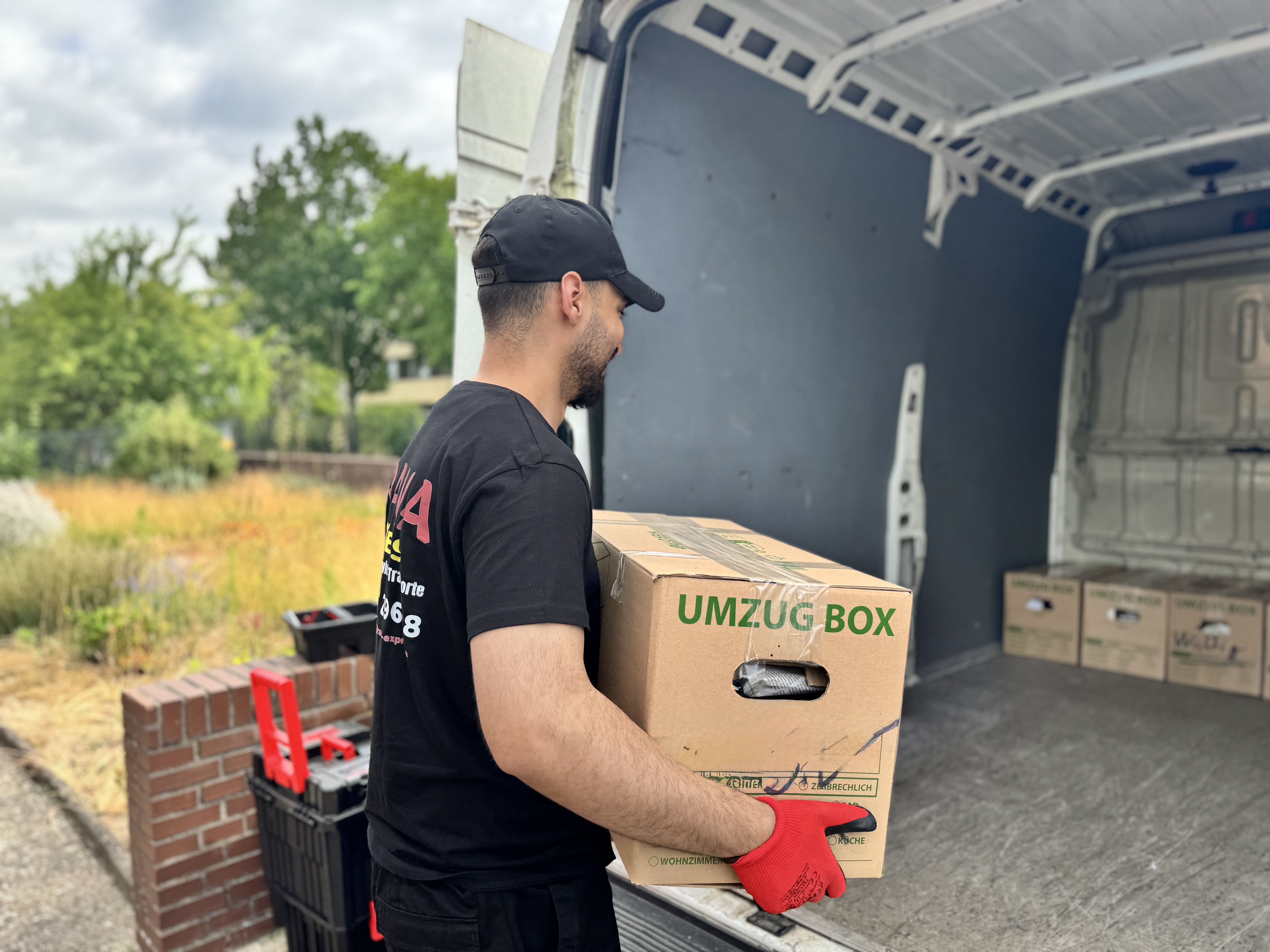 Ein Mitarbeiter verlädt einen Umzugskarton in ein Fahrzeug